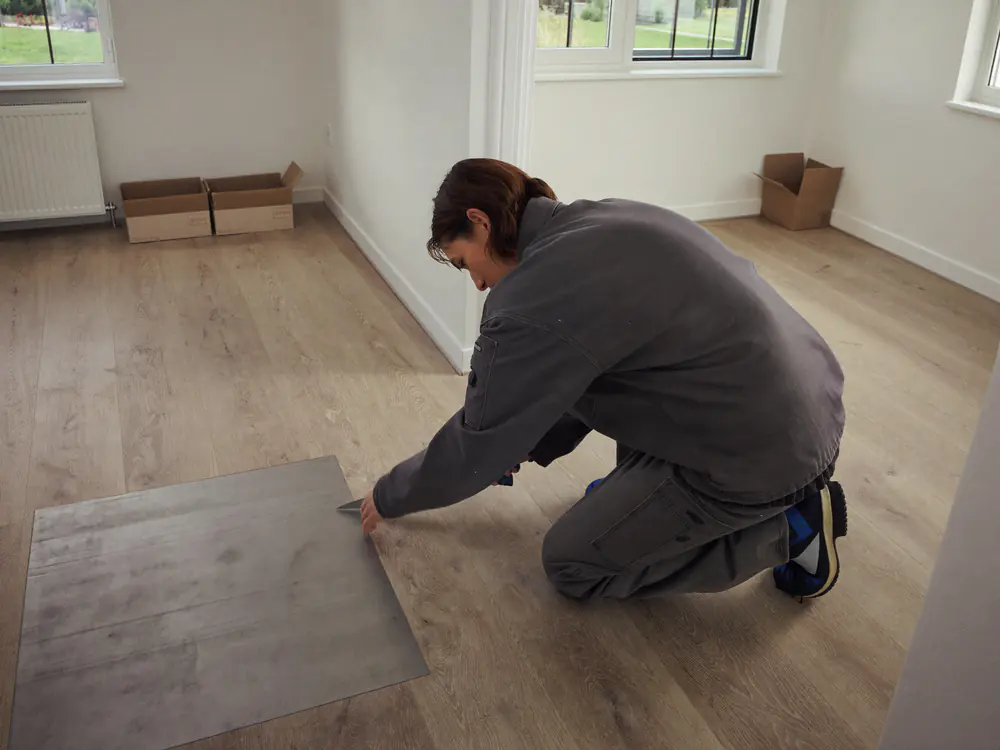 Vloerlegger snijdt een PVC plank op maat in een lichte kamer
